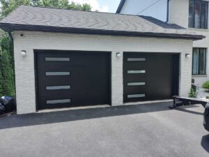 A beautiful, modern take on residential garage doors, black with four windows running from top to bottom on the left side of each garage door