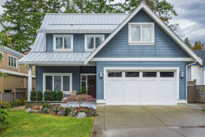 A small blue two story home with a white garage door that has four windows along the top
